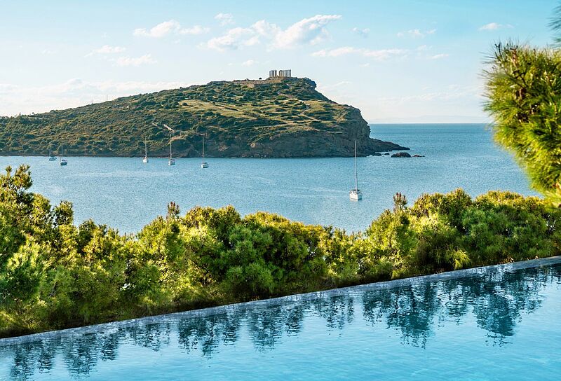 im Vordergrund ein Pool, das blaue Meer und im Hintergrund der Poseidontempel auf einer Landzunge 