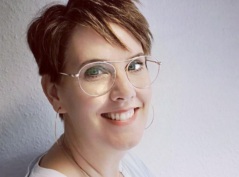 Frau lächelt in eine Kamera