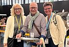 Ein Mann mit Brille in der Mitte, rechts und links zwei Frauen. Alle drei blicken in die Kamera
