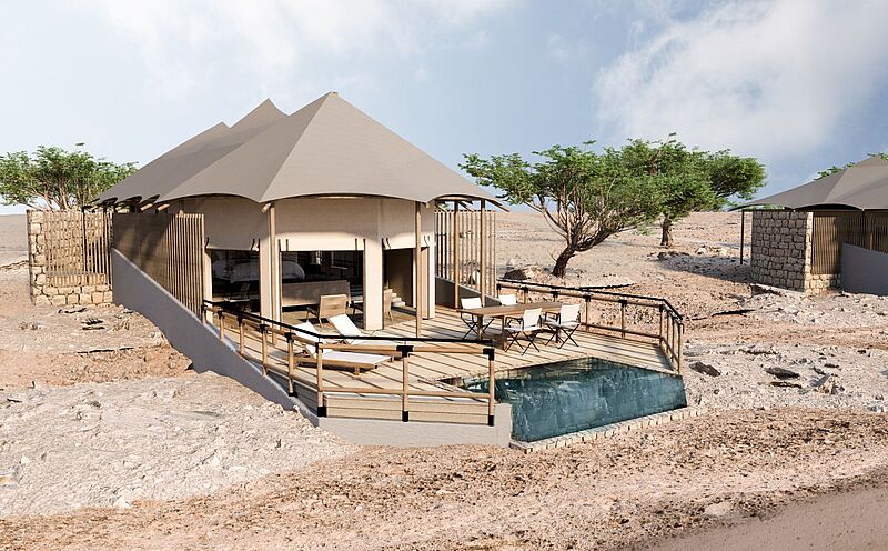 Ein luxurioses Zelt, davon eine Terrasse und ein kleiner Plunge-Pool mit blauem Wasser. Ansonsten ist alles in Naturfarben. Im Hintergrund sind einige Bäume, ansonsten wächst nichts. 