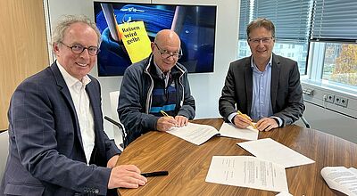 Hier wird der Kaufvertrag unterschrieben: Andreas Neumann (links) und Aquilin Schömig (rechts, Geschäftsführer des ADAC Reisevertriebs, mit Reisebüro-Inhaber Hans Doldi