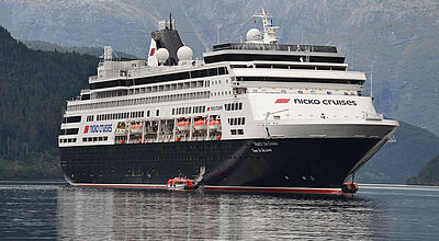 Die auf rund 1.000 Passagiere beschränkte Vasco da Gama im Hardangerfjord in Norwegen. Das Kreuzfahrtschiff Vasco da Gama mit schwarzem Rumpf ankert in einem norwegischen Fjord, umgeben von steilen Bergwänden und ruhigem Gewässer.