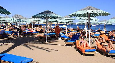 Urlauber an Strand mit Sonnenschirm