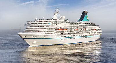 Ein Kreuzfahrtschiff mit weißem und türkisfarbenem Anstrich fährt auf offener See.