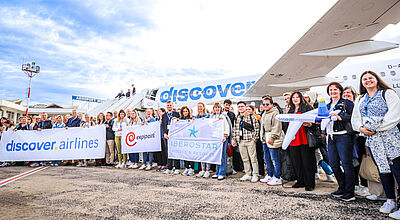 Große Gruppe von Menschen hält Banner von Discover Airlines, Expipoint und Iberostar vor einem Discover-Flugzeug am Flughafen