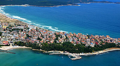 Stadt an Schwarzmeerküste mit Strand und Bergen im Hintergrund im Sonnenschein