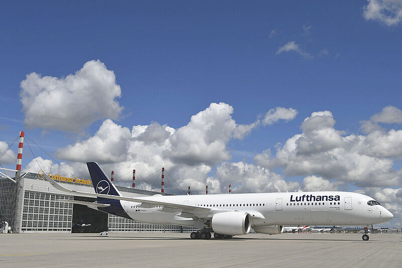 Lufthansa, hier ein Airbus A350, baut auch auf der Fernstrecke aus. Ein Flugzeug vom Typ Airbus A350 von Lufthansa in weiß-blauer Lackierung steht vor einem Hangar der Lufthansa Technik