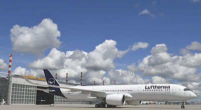 Lufthansa, hier ein Airbus A350, baut auch auf der Fernstrecke aus. Ein Flugzeug vom Typ Airbus A350 von Lufthansa in weiß-blauer Lackierung steht vor einem Hangar der Lufthansa Technik