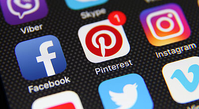 Auf einem schwarzen Smartphone-Hintergrund sind Apps wie Facebook, Instagram und Pinterest abgebildet. Bei dem Pinterest-Icon ist eine Benachrichtigung in Form der Ziffer 1 zu sehen.
