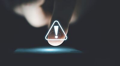 Finger vor schwarzem Hintergrund zeigt auf Smartphone Warnhinweis