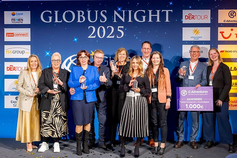 Das sind die Reisebüro-Sieger der Globus Awards 2024. Die Aufnahme zeigt eine Gruppe von ausgezeichneten Reisebüro-Mitarbeitern bei der Preisverleihung Globus Night 2025, die stolz ihre Trophäen und einen Scheck im Wert von 1.000 Euro präsentieren. Die Kulisse ist mit Sponsoren-Logos und dem Schriftzug der Veranstaltung gestaltet.