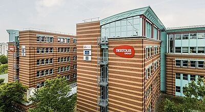 Modernes Bürogebäude der DER Touristik Group in Frankfurt, rote Backsteinoptik mit Glaselementen und Logo.