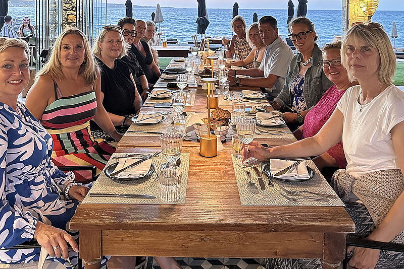 Gruppe von Menschen sitzt auf Kreta zusammen in einem Restaurant am Tisch