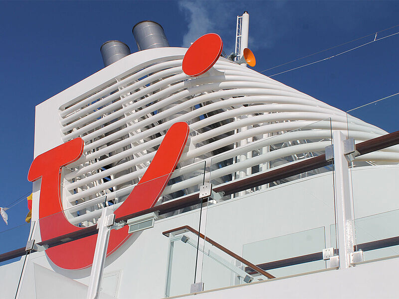 Schornstein eines Kreuzfahrtschiffes mit dem roten Smiley-Logo von TUI.