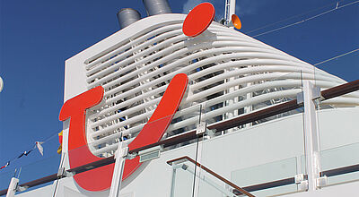 Schornstein eines Kreuzfahrtschiffes mit dem roten Smiley-Logo von TUI.