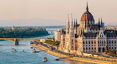 Landschaftsbild von einer Stadt am Fluss mit einem imposanten Gebäude.