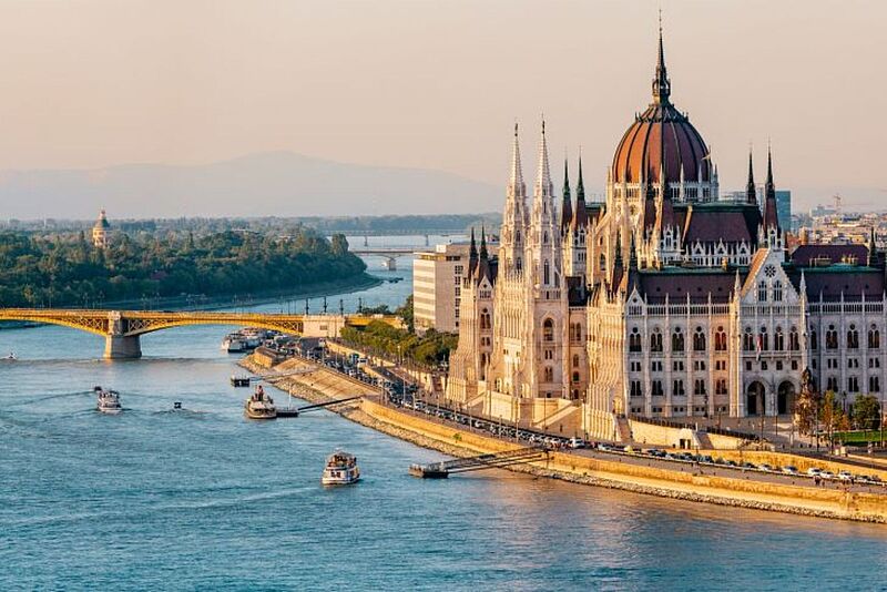 Landschaftsbild von einer Stadt am Fluss mit einem imposanten Gebäude.