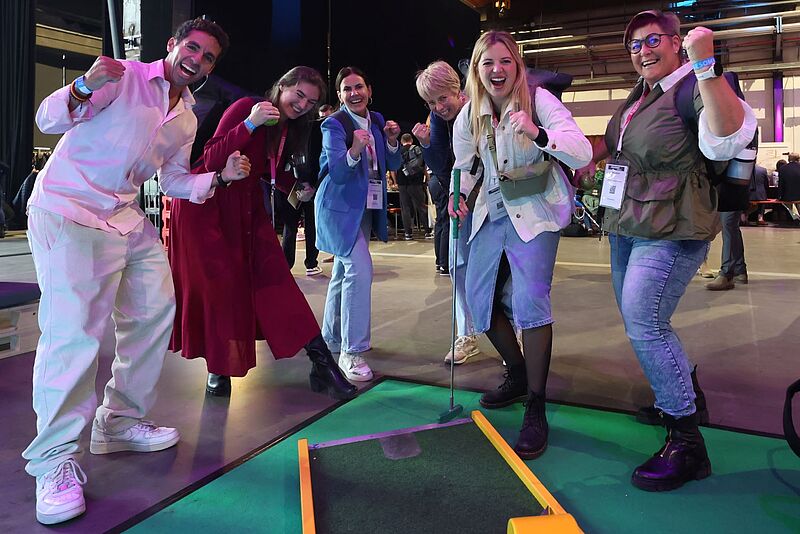 Eine Gruppe fröhlicher Menschen vor einer Minigolfbahn