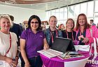 Fünf Frauen an einem Stand lächeln in die Kamera
