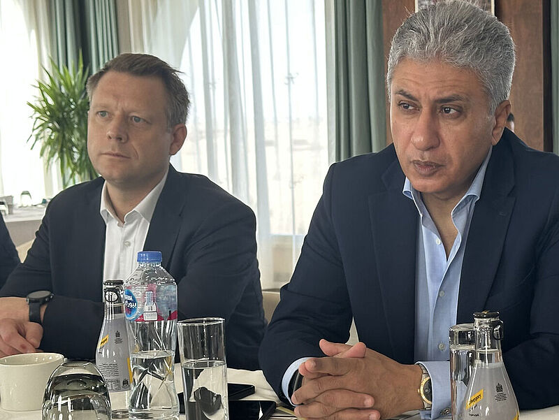 Geschäftstreffen mit zwei Männern in Anzügen an einem Konferenztisch im Xanadu Makadi Bay Resort, Getränke und Gläser auf dem Tisch.