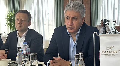 Geschäftstreffen mit zwei Männern in Anzügen an einem Konferenztisch im Xanadu Makadi Bay Resort, Getränke und Gläser auf dem Tisch.
