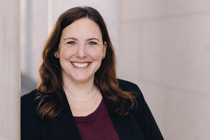 Freut sich über die Anbindung an die Paxlounge: Jennifer Horn, Head of Sales und Prokuristin bei Bavaria Fernreisen. Porträt einer lächelnden Frau mit schulterlangen braunen Haaren. Sie trägt eine dunkle Jacke über einem bordeauxfarbenen Shirt und steht vor einem hellen, unscharfen Hintergrund.