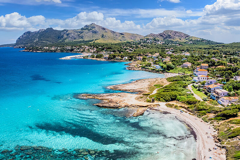 Luftaufnahme der Küste bei Cala Ratjada, Mallorca, mit türkisblauem Meer, Sandstränden, weißen Häusern und der Serra de Llevant im Hintergrund.
