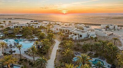 Luxuriöses Wüsten-Resort mit modernen Villen, Palmen, Pools und Sonnenuntergangspanorama am Rande der Sahara bei Tozeur, ideal für entspannenden Urlaub in Tunesien