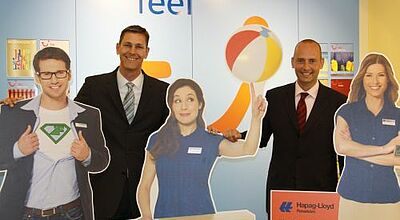 Wollen die Reiseverkäufer stärker an die eigene Marke binden: TLT-Manager Peter Wittmann (Filialvertrieb, rechts) und Dirk Hansel (Franchise-Büros) zwischen werbenden Pappfiguren.