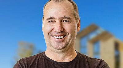 Foto von einem lächelnden Mann vor blauem Hintergrund.