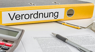 Aktenordner mit Aufschrift "Verordnung", Taschenrechner, Stift und Dokumente auf einem Schreibtisch. Tarifverhandlungen, Touristik, DRV-Tarifgemeinschaft, Verdi