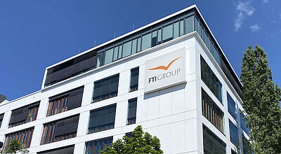 Im Zuge der FTI-Insolvenz klagen Verbraucher gegen Reisevermittler. Archivbild: FTI Eckansicht eines modernen Bürogebäudes. Auf der weißen Fassade prangt in orangefarbenen Buchstaben der Firmenname FTI.