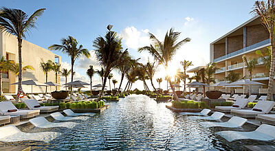 Ein Pool mit Liegen im Wasser. Auf beiden Seiten Gebäude