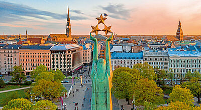 Das Freiheitsdenkmal ist das Wahrzeichen Rigas Stadtpanorama Riga mit Freiheitsdenkmal im Vordergrund, historische Altstadt mit Kirchtürmen, Herbstbäume und Abendhimmel.