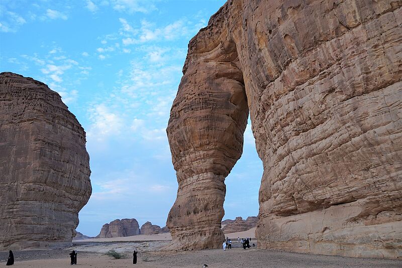 Wüstenlandschaft mit großen roten Felsen im Vordergrund ein Felstor