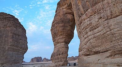 Wüstenlandschaft mit großen roten Felsen im Vordergrund ein Felstor