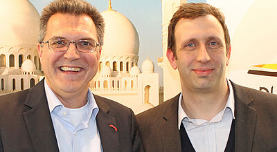 Andreas Heimann (links) und Ralf Hieke auf der ITB vor einer Werbewand für die DRV-Jahrestagung Anfang Dezember in Abu Dhabi