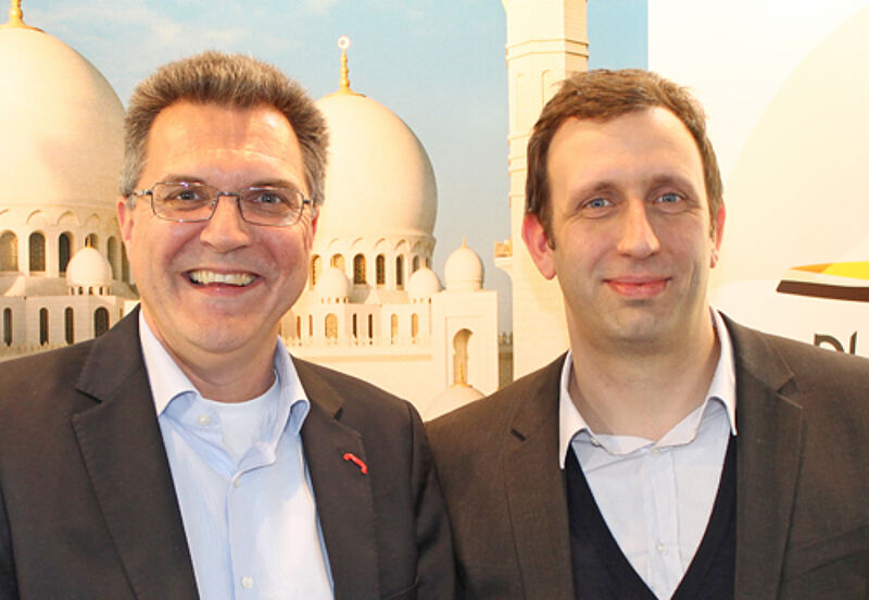 Andreas Heimann (links) und Ralf Hieke auf der ITB vor einer Werbewand für die DRV-Jahrestagung Anfang Dezember in Abu Dhabi