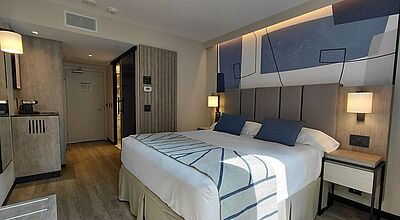 Modernes Hotelzimmer im Riu Plaza Toronto mit King-Size-Bett, stilvoller Wanddekoration, Nachttischen und stimmungsvoller Beleuchtung