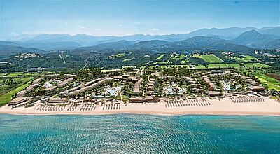 Hinter einem langen Sandstrand befinden sich viele Hotelgebäude, die an mehreren Pools liegen