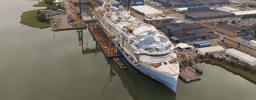 Luftaufnahme der Schiffswerft Meyer Turku in Finnland mit dem noch nicht ganz fertiggestellten Kreuzfahrtschiff Legend of the Seas.