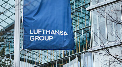 Eine blaue Flagge mit Lufhansa-Schriftzug weht vor der Konzernzentrale der Airline-Gruppe