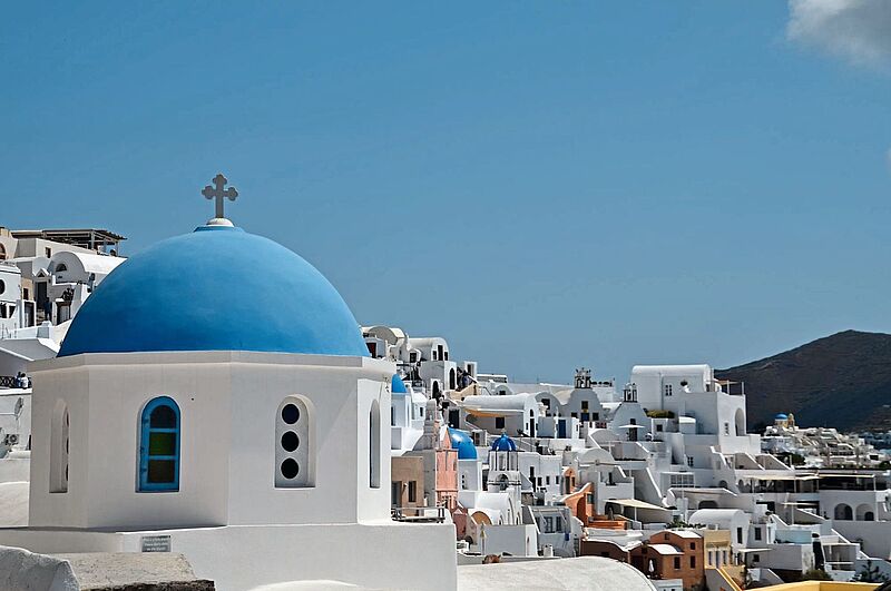 Eine für die griechische Insel Santorin typische blaue Kuppel erhebt sich über einem Ort