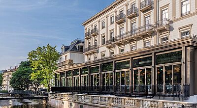 Luxuriöses Hotel Europäischer Hof in Baden-Baden mit eleganter Fassade, Balkonen und Terrasse am Wasserkanal im Abendlicht