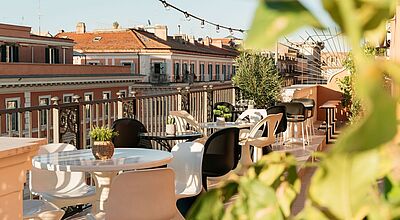 Stylische Rooftop-Terrasse im Ruby Giulia Hotel in Rom mit modernen Sitzmöbeln, Pflanzen und Blick auf historische Häuserfassaden – perfekter Ort für Städtereisen in Italien.