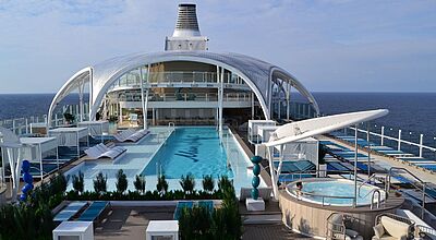 Das erste von zwei bestellten Schiffen der neuen Intuition-Klasse ist jetzt in Dienst gestellt. Foto: ck Pooldeck eines Kreuzfahrtschiffs mit 25 Meter langem Schwimmbecken, das tels von einer großen weißen Kuppelkonstruktion überspannt ist
