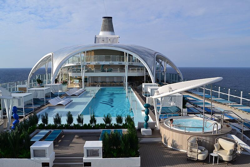 Pooldeck eines Kreuzfahrtschiffs mit 25 Meter langem Schwimmbecken, das tels von einer großen weißen Kuppelkonstruktion überspannt ist