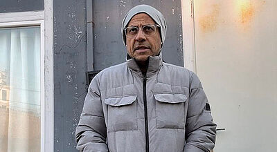 Mann in Winterjacke vor Container