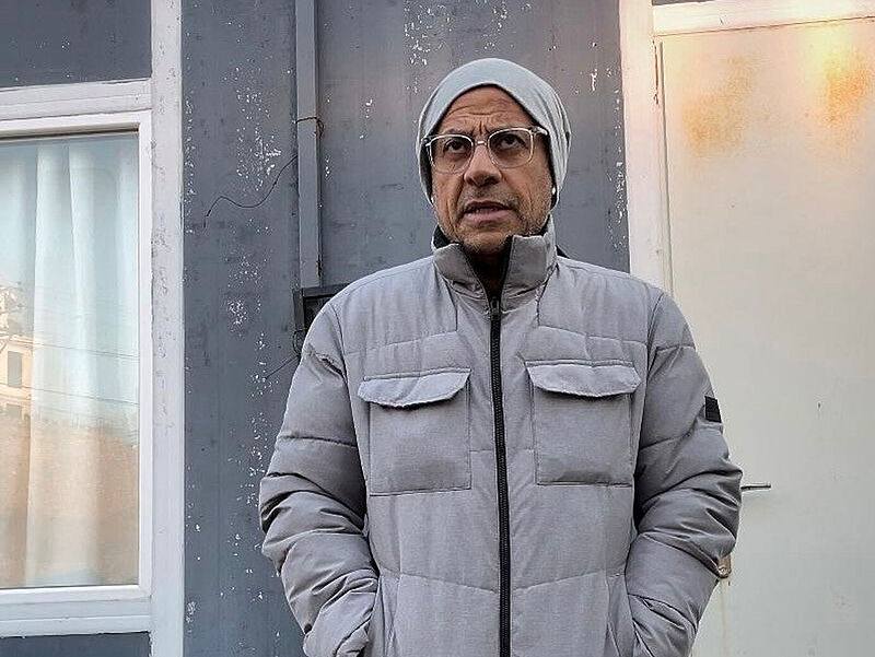 Mann in Winterjacke vor Container
