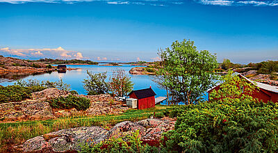Ein rotes Holzhaus, ein Bootssteg und ganz viel Wasser drumherum: So sieht ein typisches Grundstück auf den Aland-Inseln aus